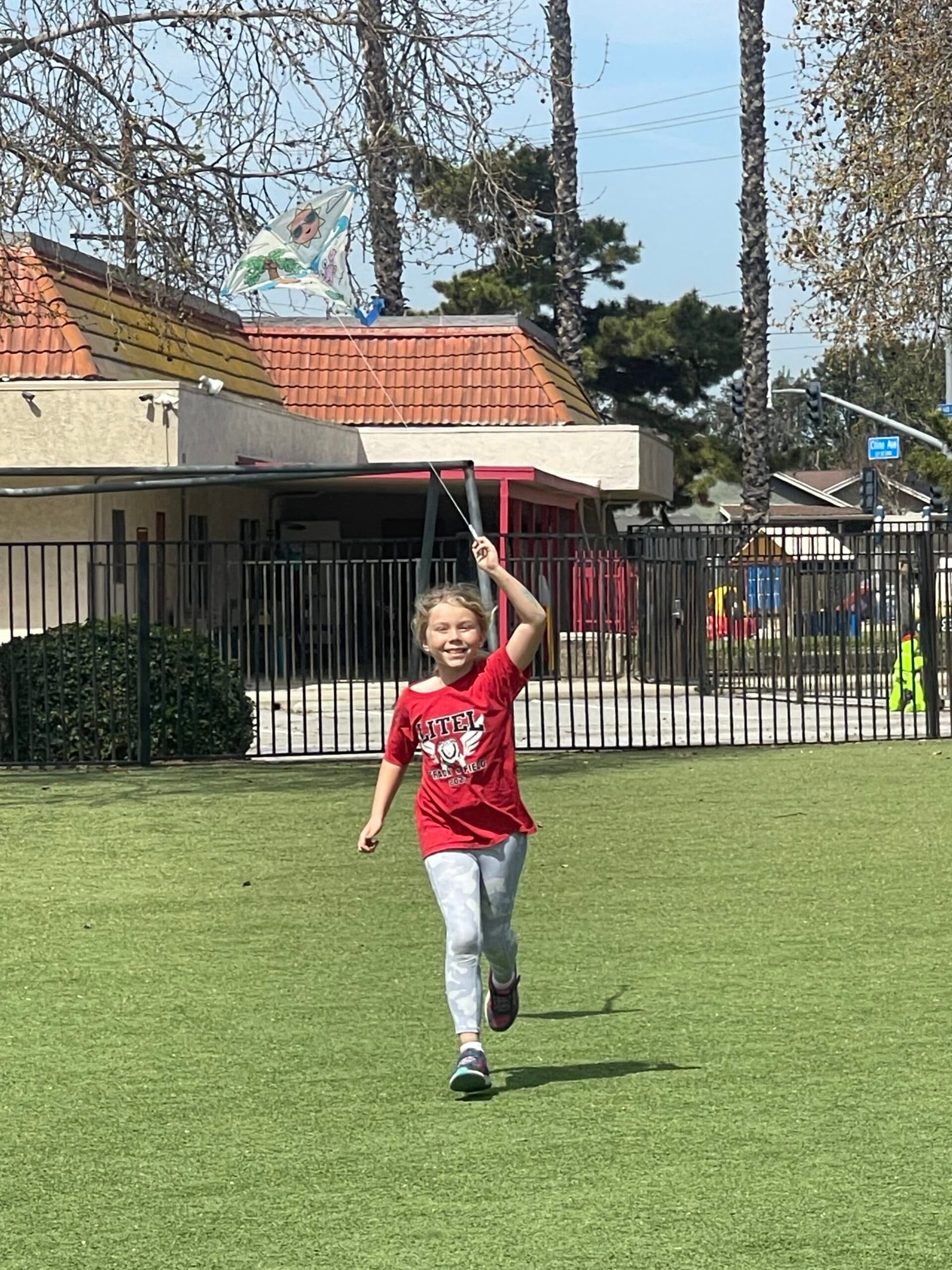 Student flying a kite across the playground field
