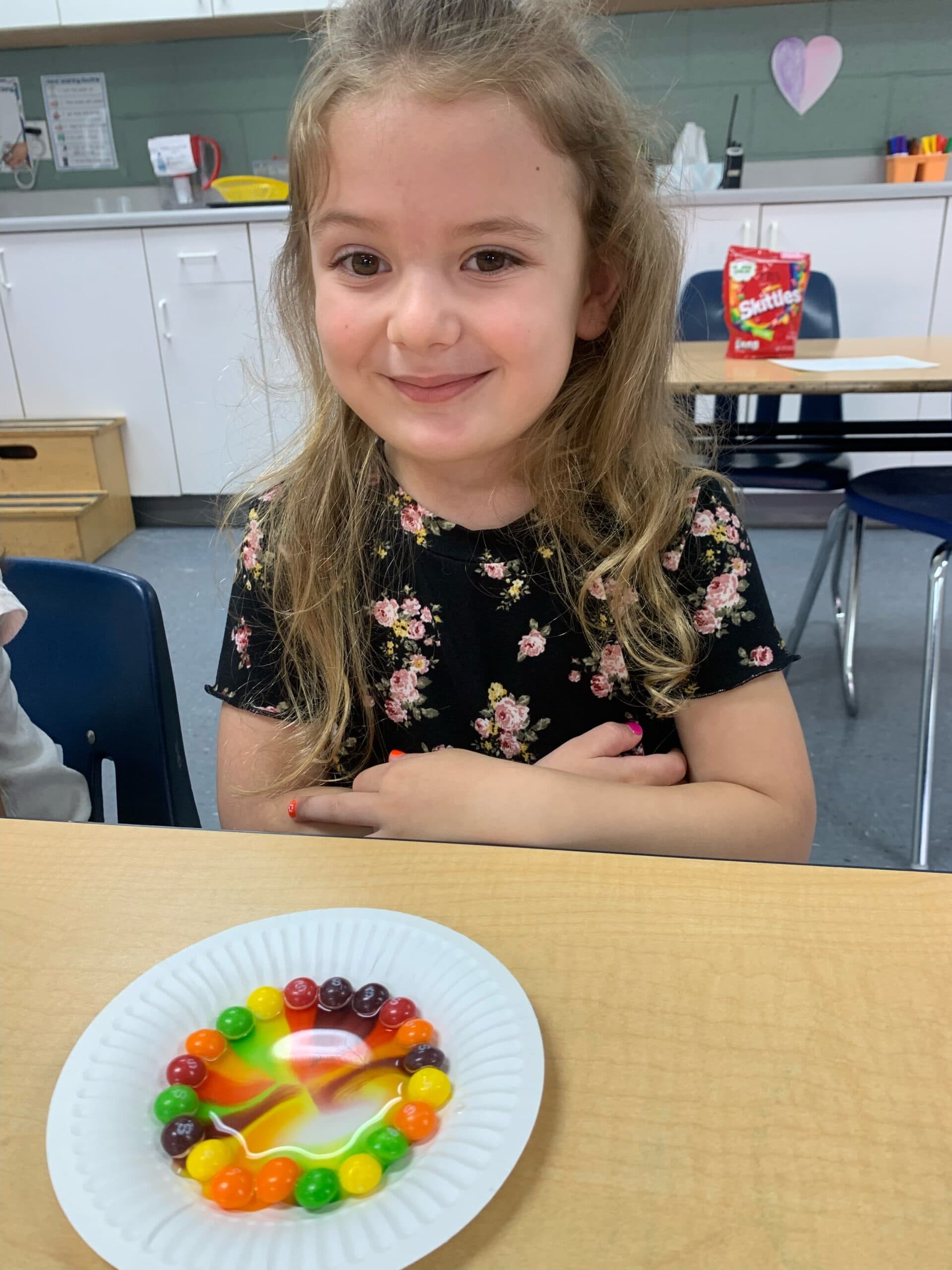 Student pointing at a colorful classroom art project