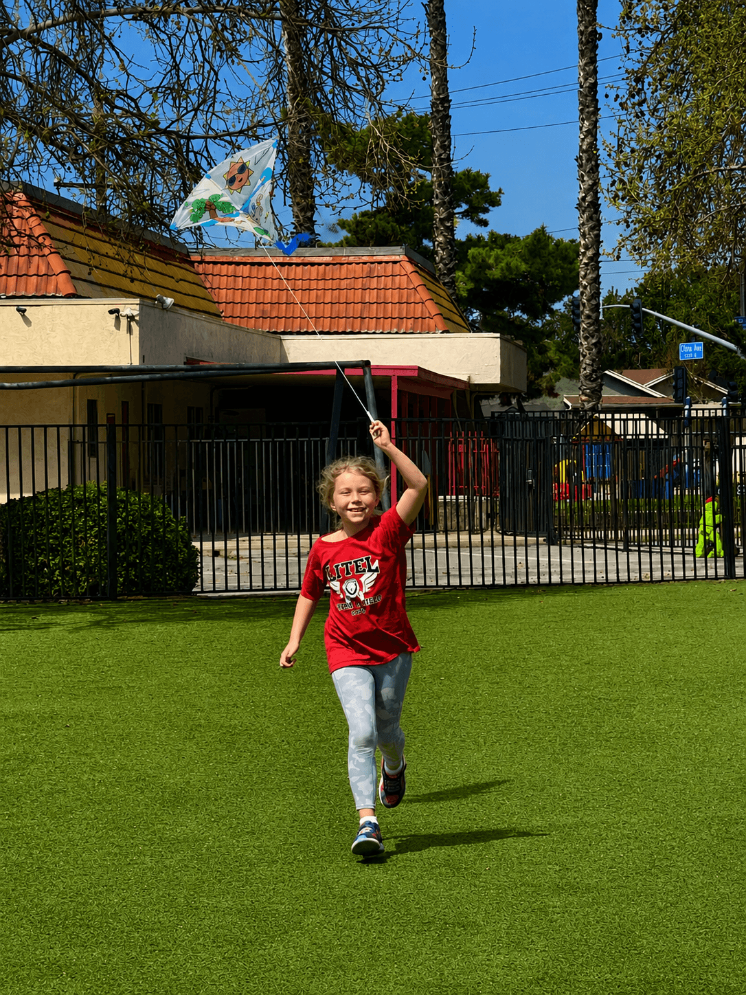 Student flying a kite across the playground field