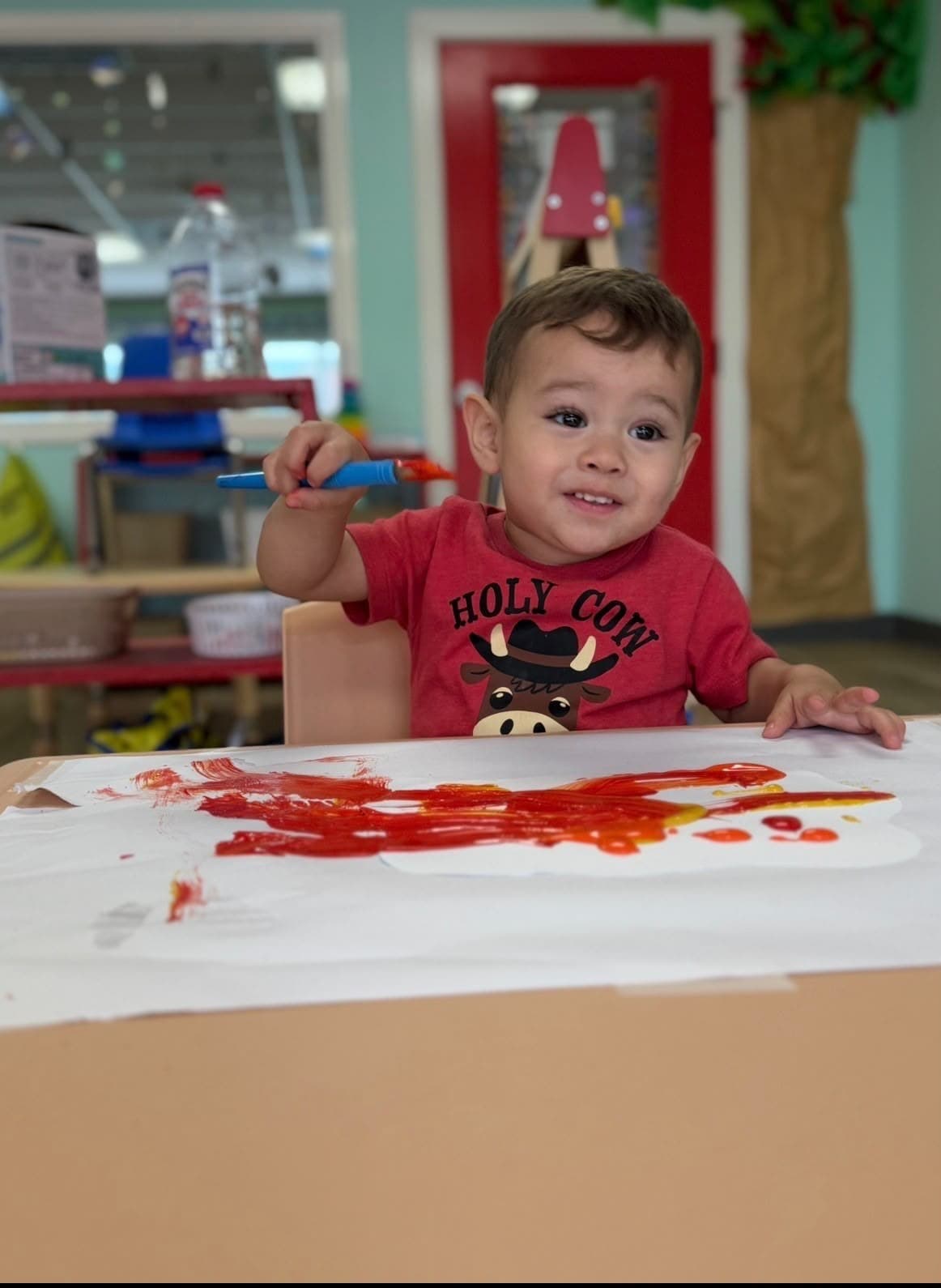 Student pointing at a colorful classroom art project